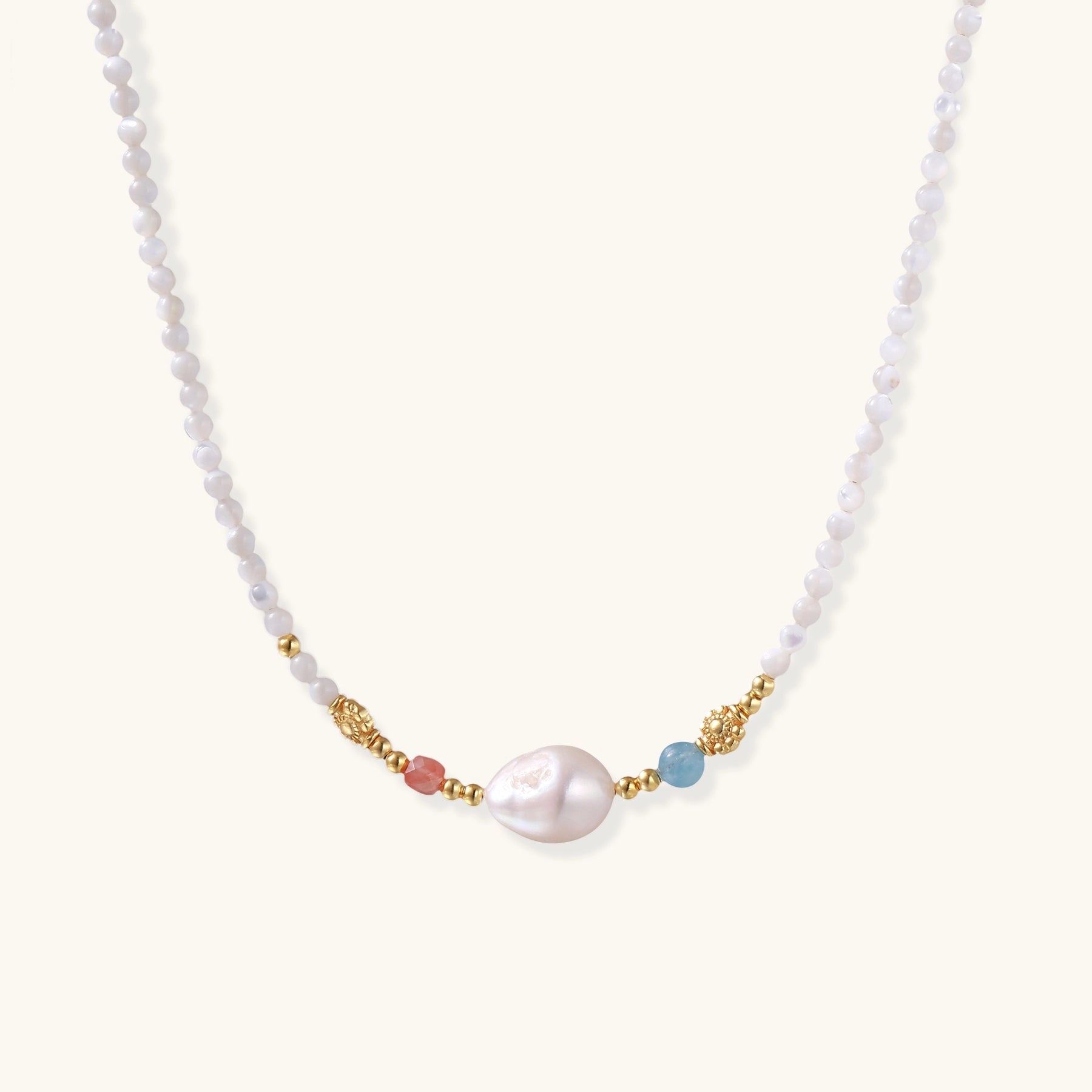 Delicate white beaded necklace with central freshwater pearl and gold-toned emerald accents on white background.
