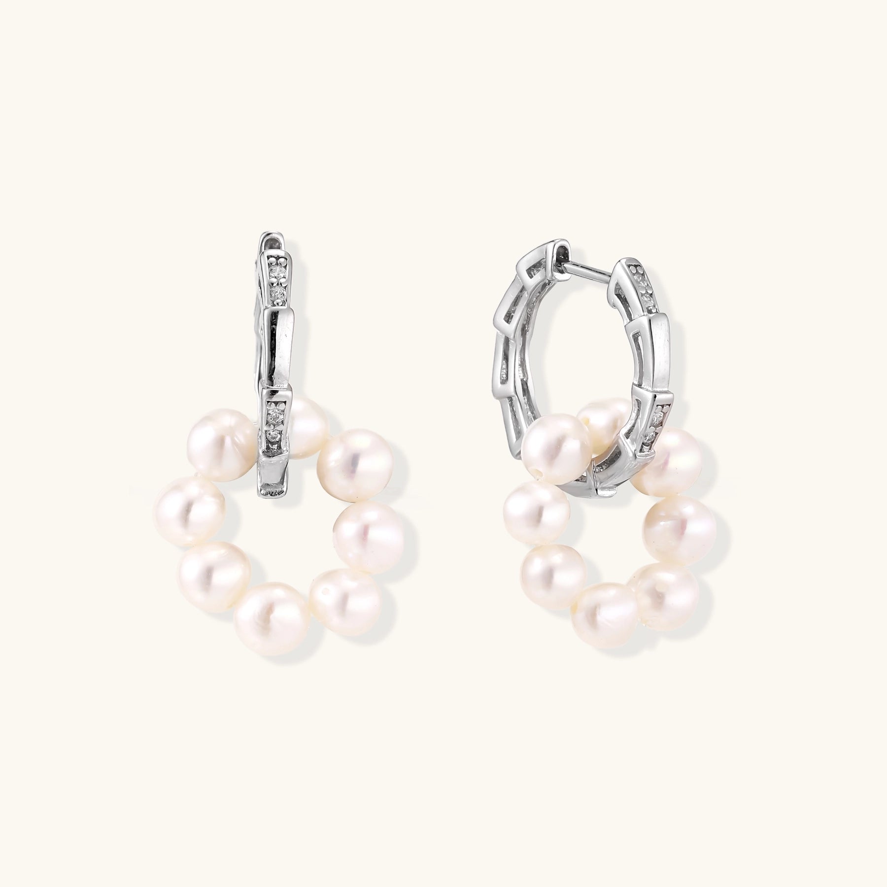 Sterling silver huggie hoop earrings with clustered white freshwater pearls and crystal accents on white background.