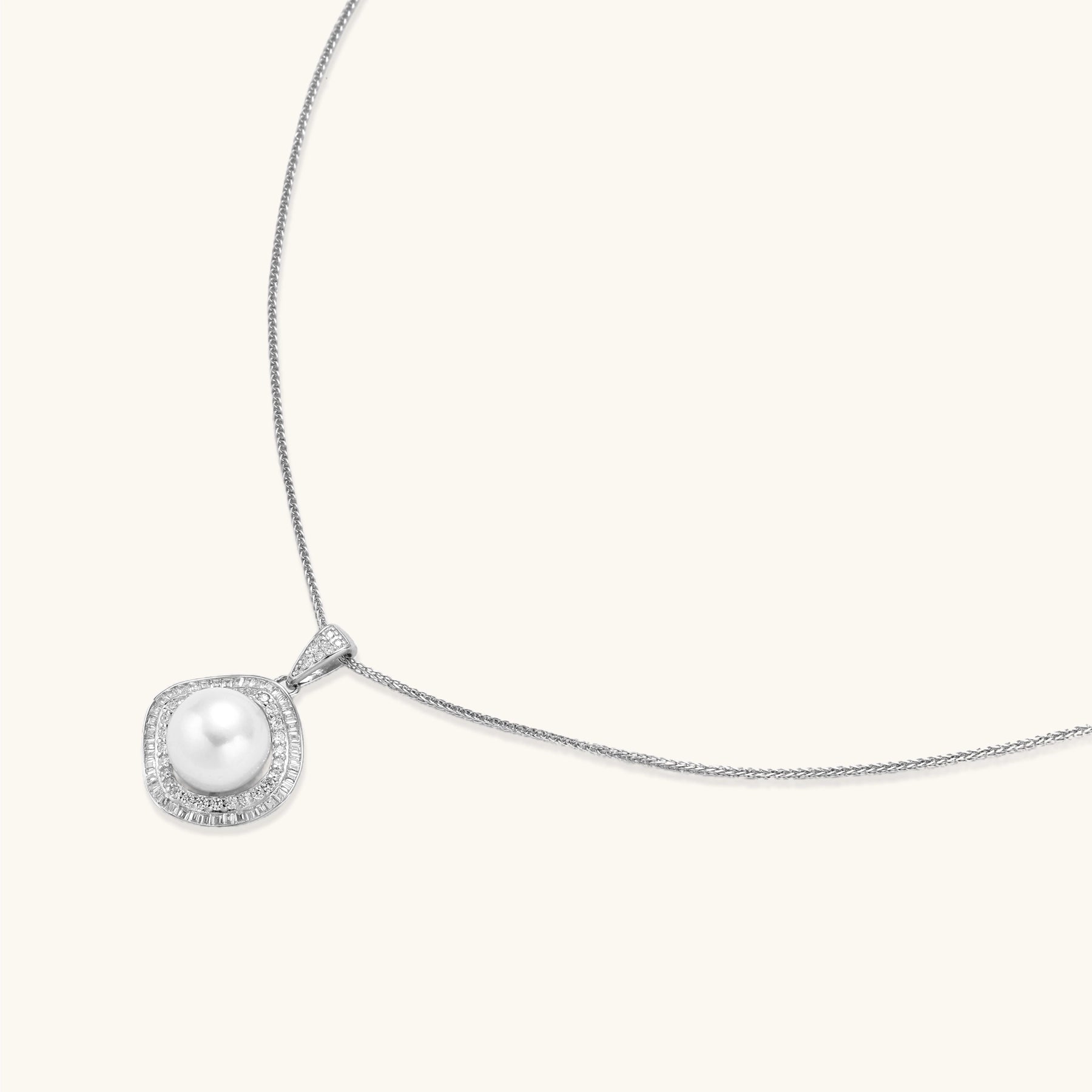 Sterling silver necklace with geometric halo setting surrounding a 10mm freshwater pearl on white background.