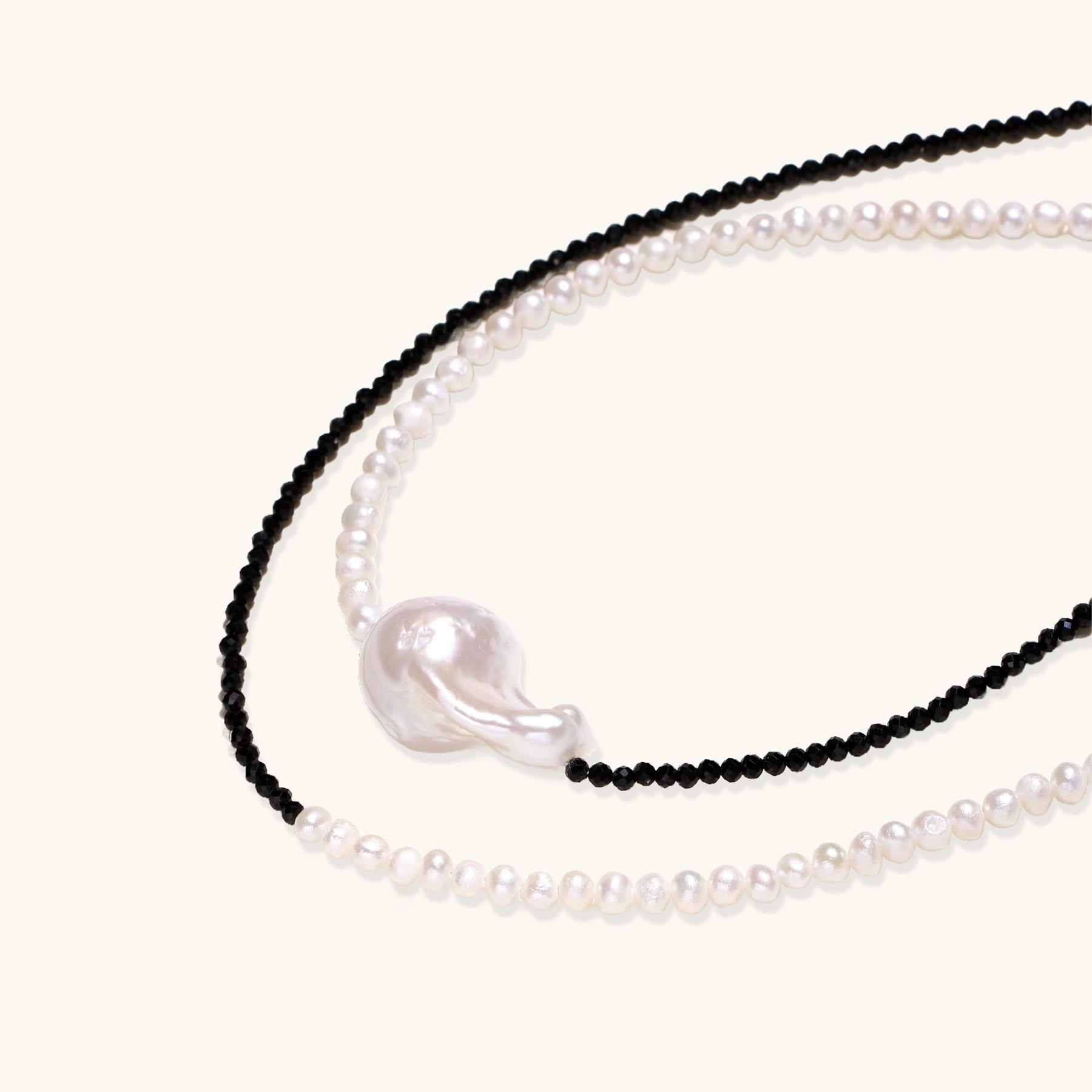 Two-strand necklace with black crystal beads and white pearls featuring a large baroque pearl centerpiece on white background.