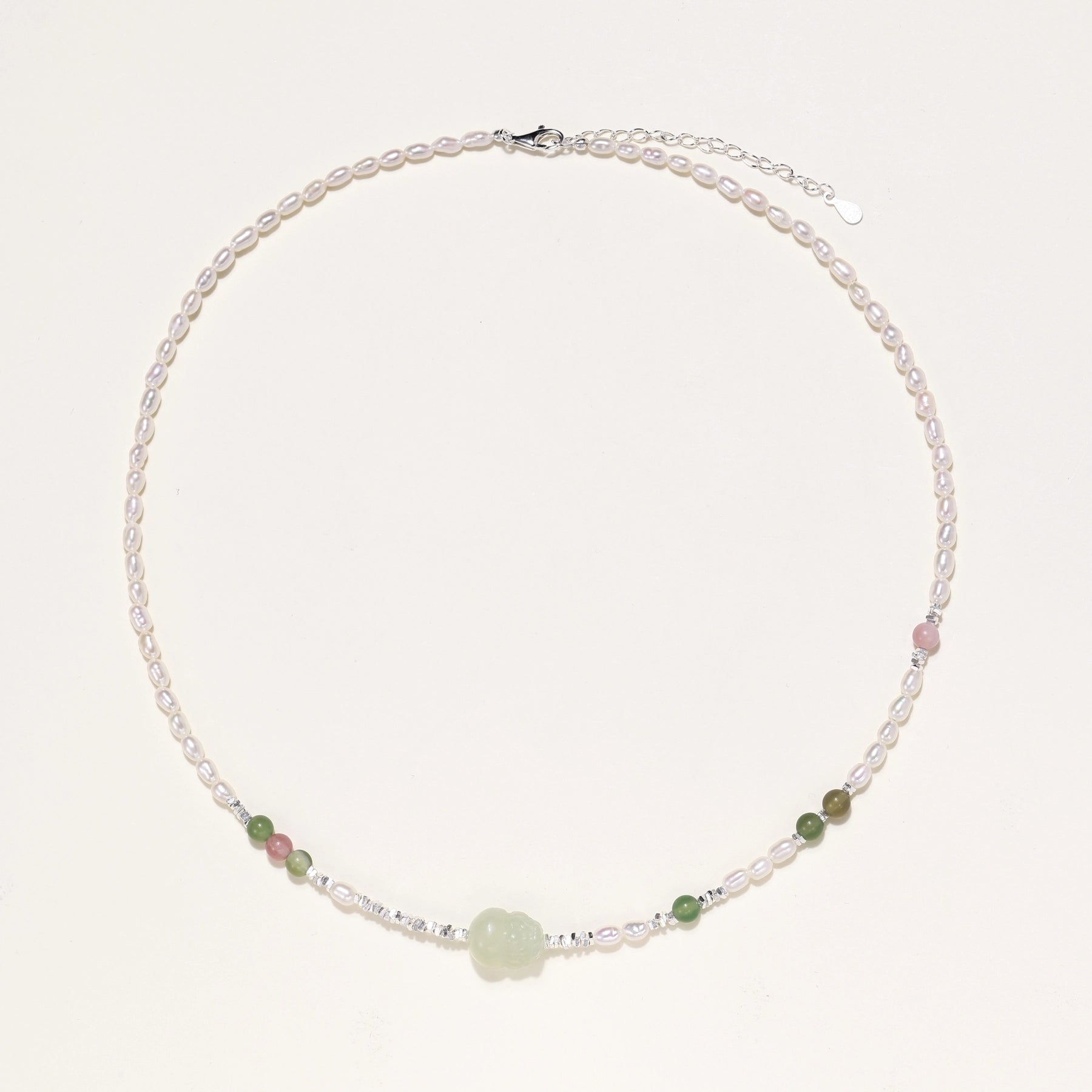 Delicate sterling silver necklace with freshwater pearls, green serpentine centerpiece, and mixed agate beads on white background.