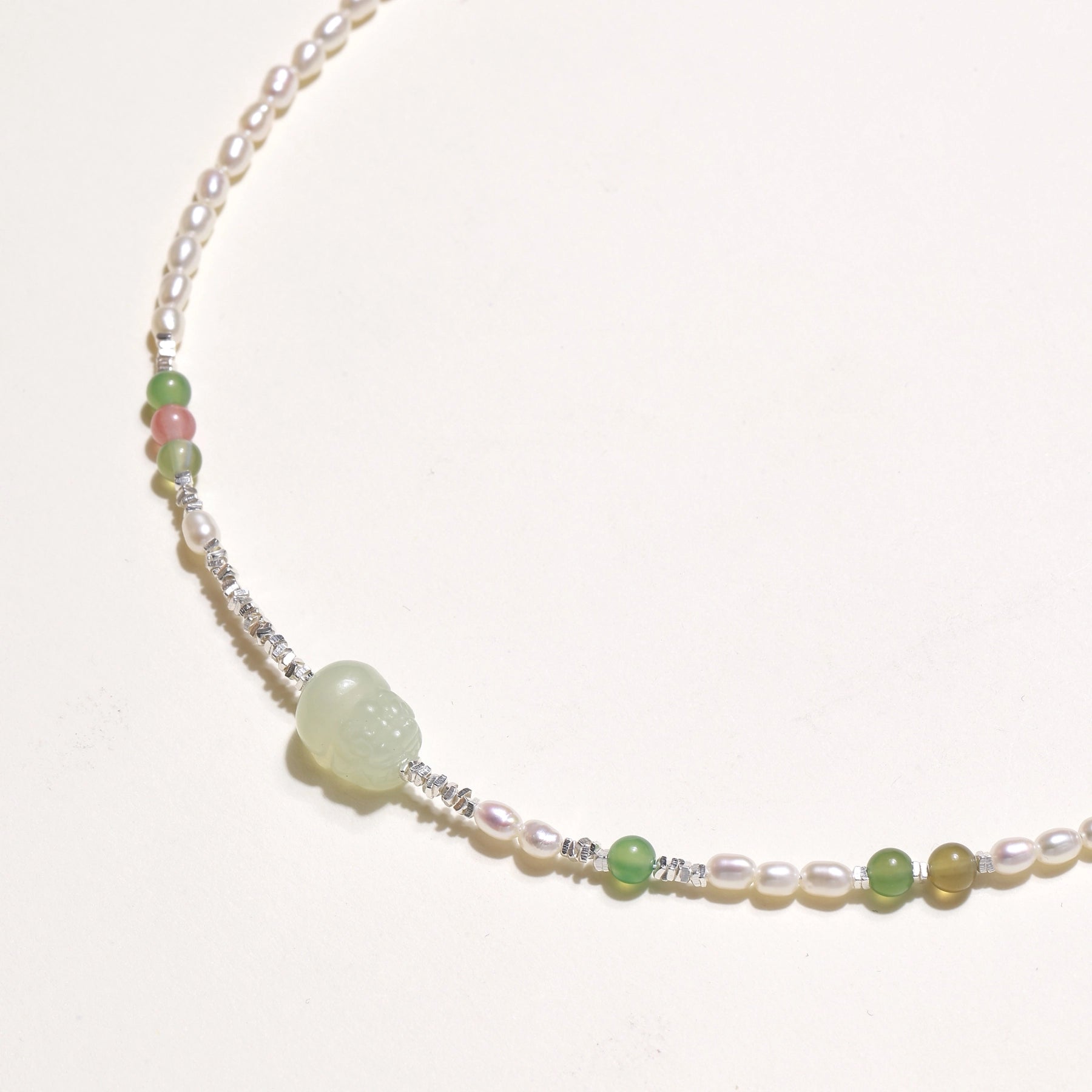 Delicate sterling silver necklace with freshwater pearls, green serpentine centerpiece, and mixed agate beads on white background.