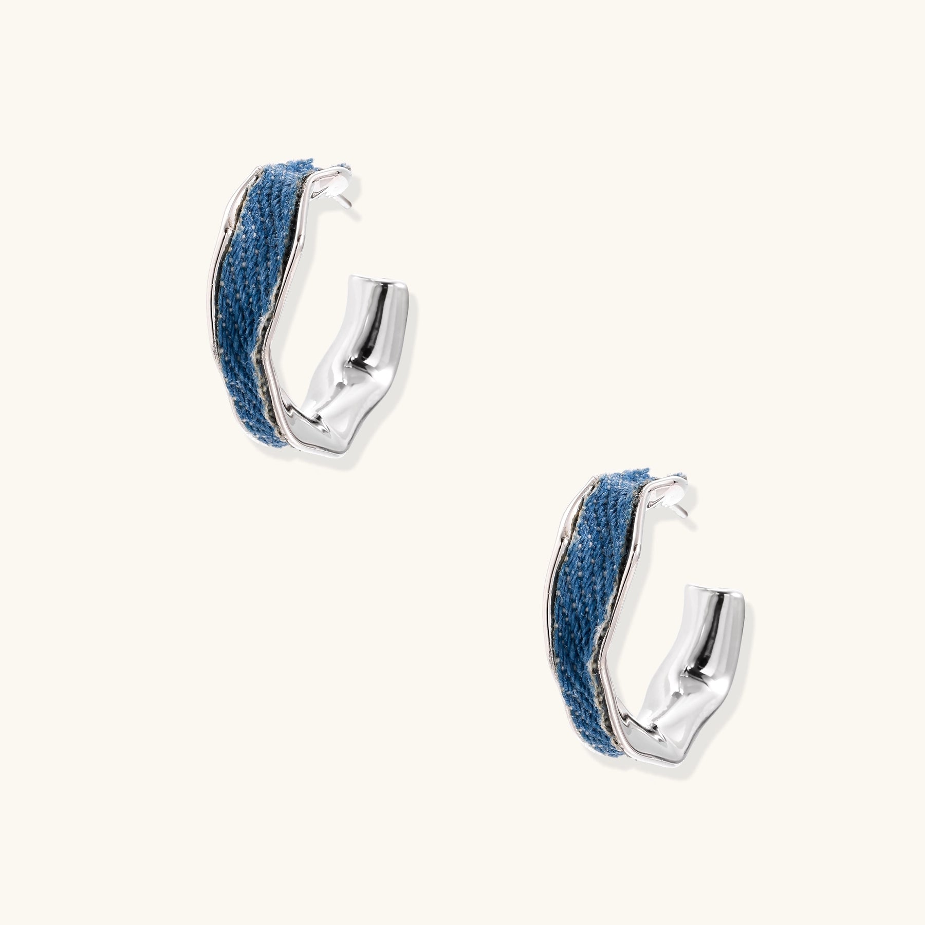 Small gold-plated hoop earrings with blue denim fabric insets on white background, showing casual-luxe styling.