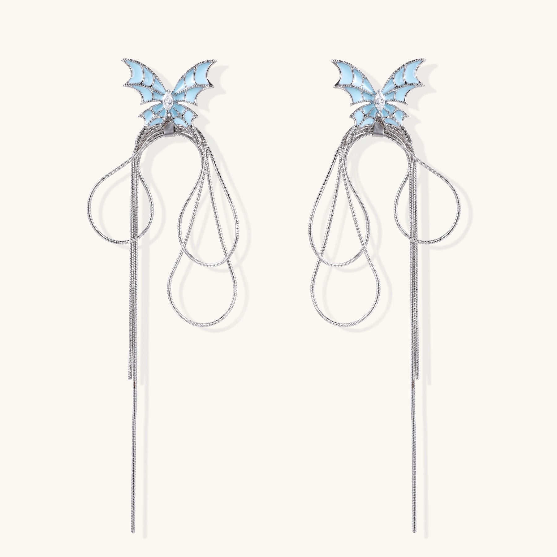 Blue enamel butterfly earrings with cascading gold-plated chains and zirconia crystal accents on white background.