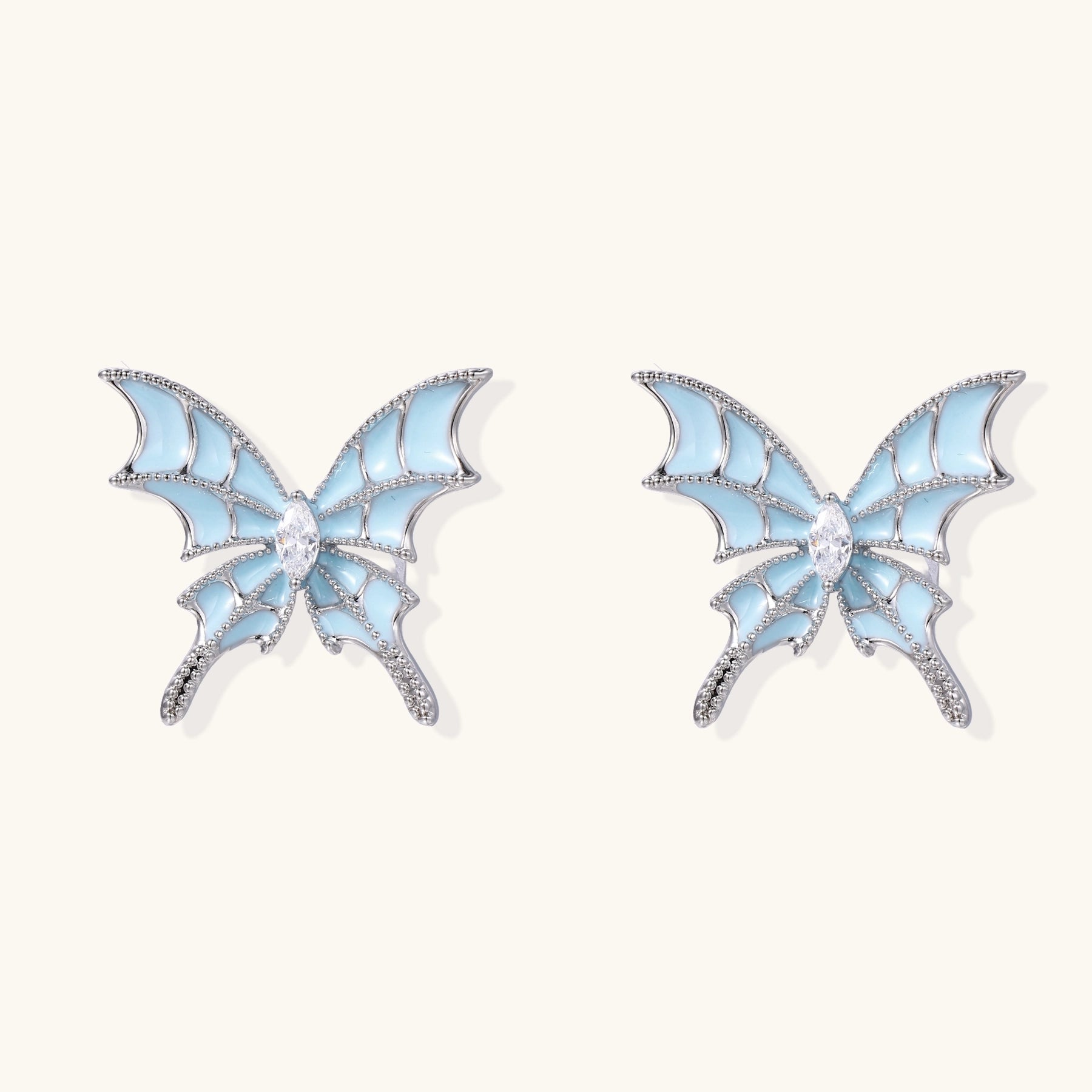 Blue enamel butterfly earrings with cascading gold-plated chains and zirconia crystal accents on white background.