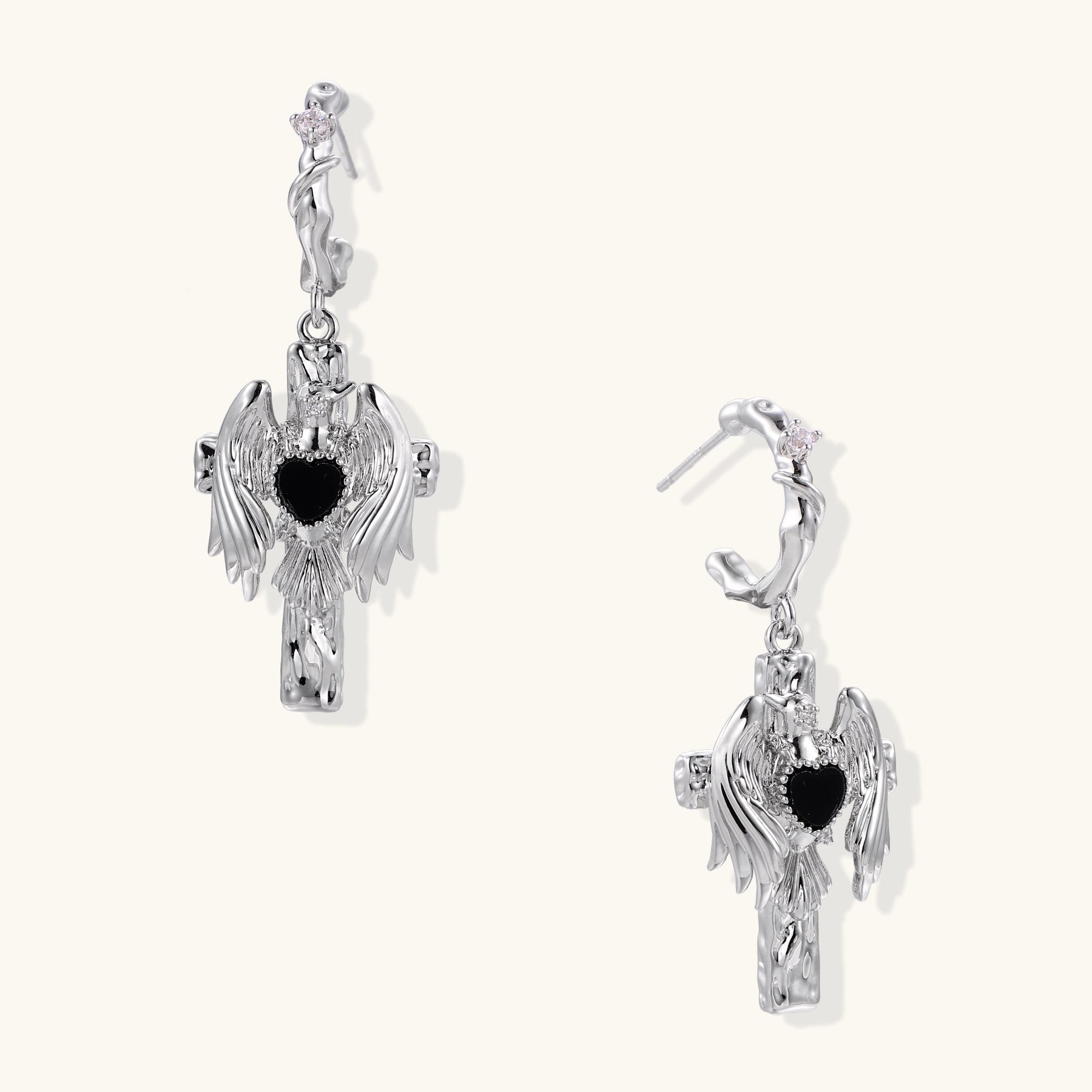 Gold-plated brass earrings with winged design, black heart-shaped zirconia center, and crystal accents on white background.
