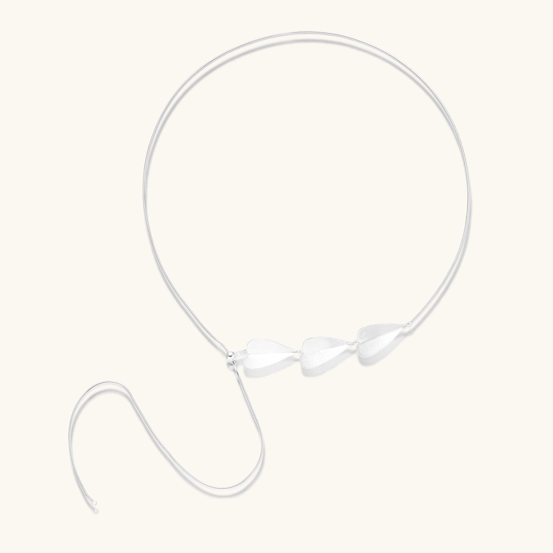 Delicate sterling silver necklace with brushed leaf pendants distributed along a fine chain on white background.