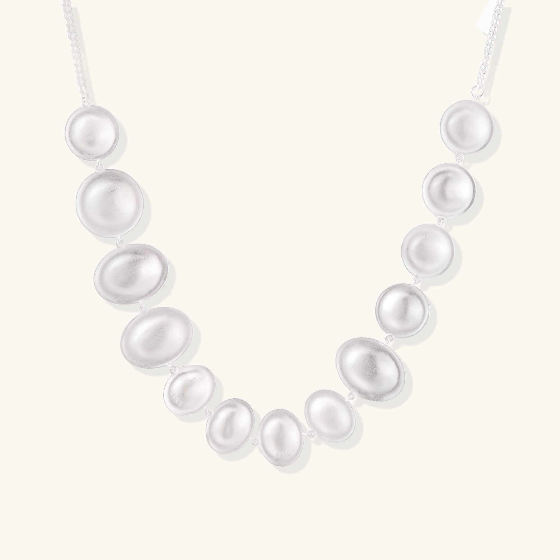 Sterling silver necklace with asymmetrically placed white pearls of varying sizes on neutral background