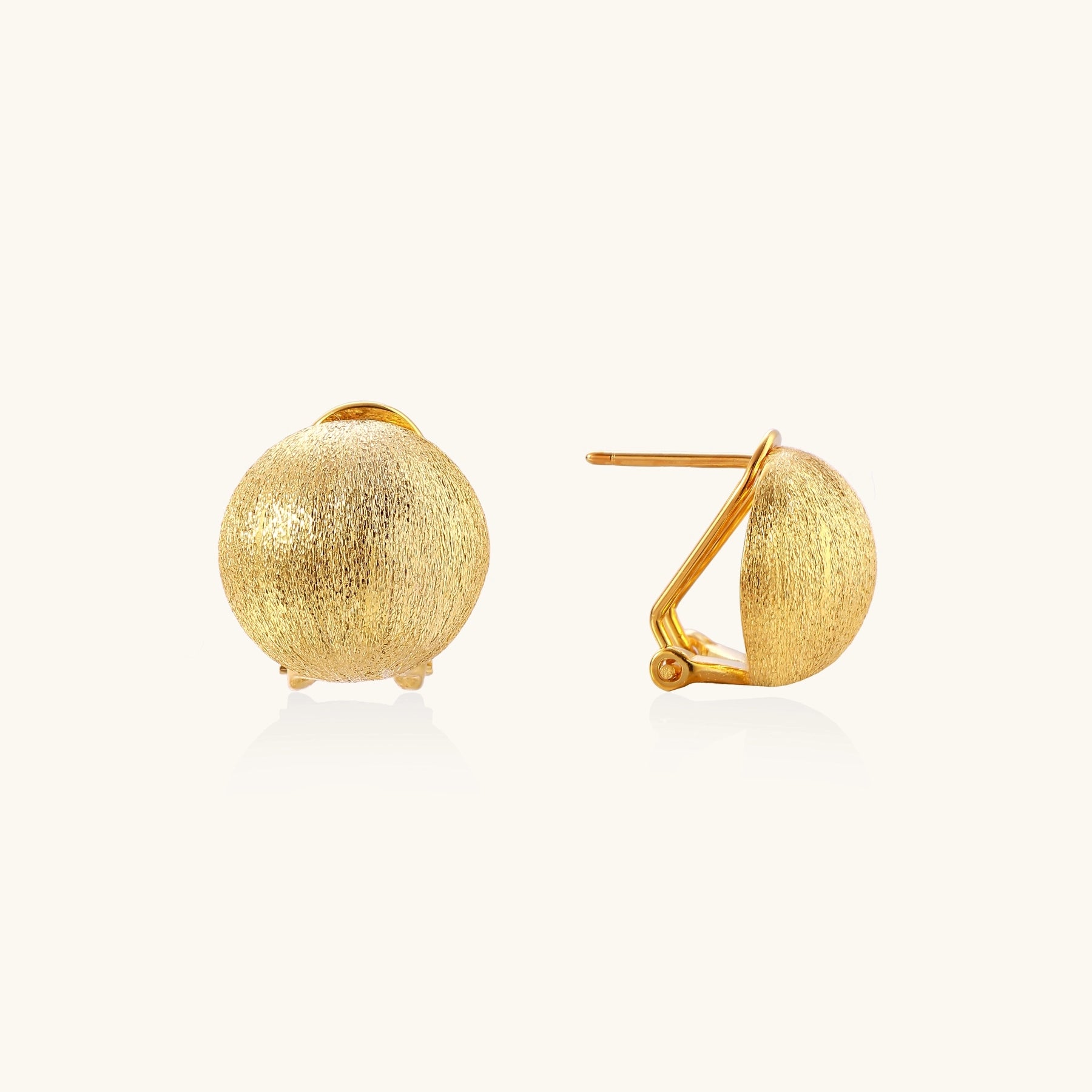 Close-up of textured gold-plated sterling silver dome clip-on earrings with brushed finish on white background.