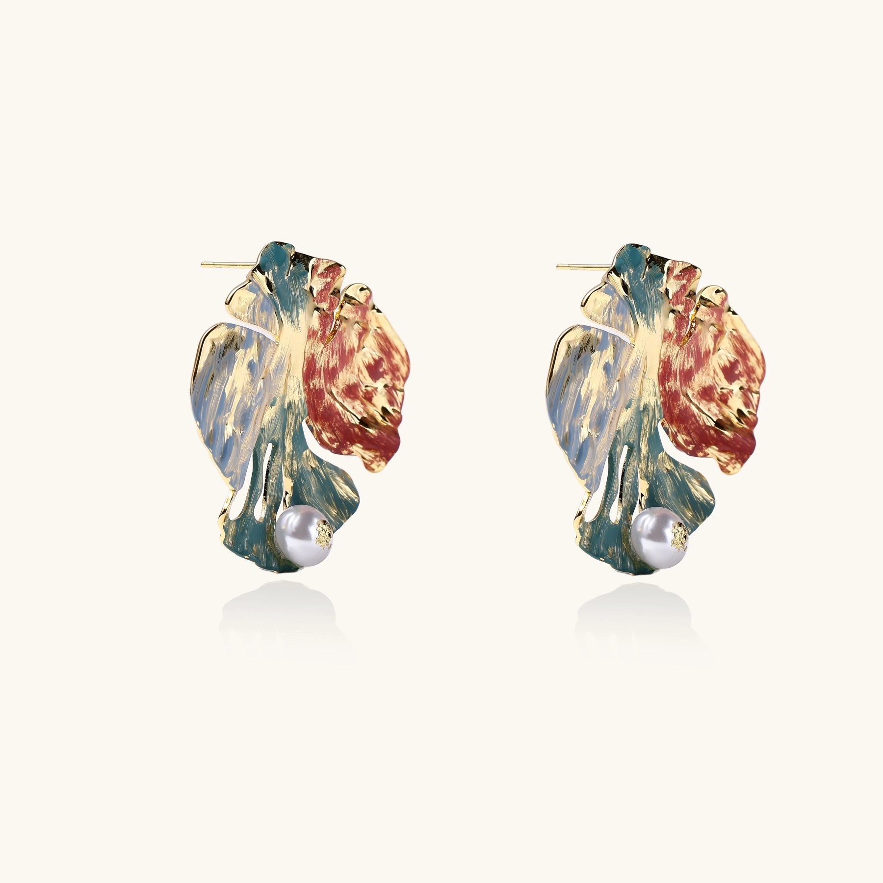 Colorful enamel monstera leaf earrings with pearl accents in teal, coral and gold tones on neutral background.