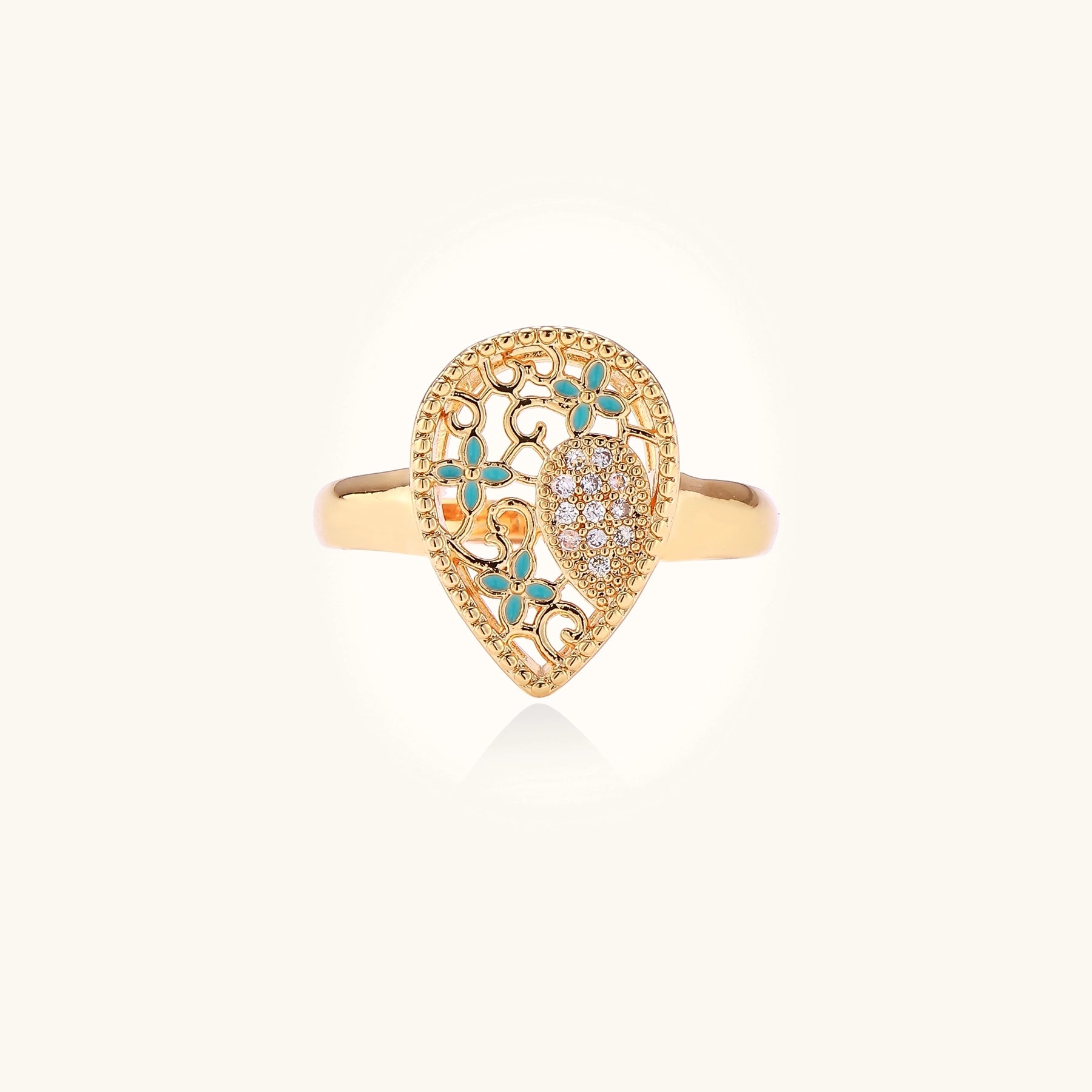 Gold-plated heart ring with turquoise enamel scrollwork and cubic zirconia stones on white background