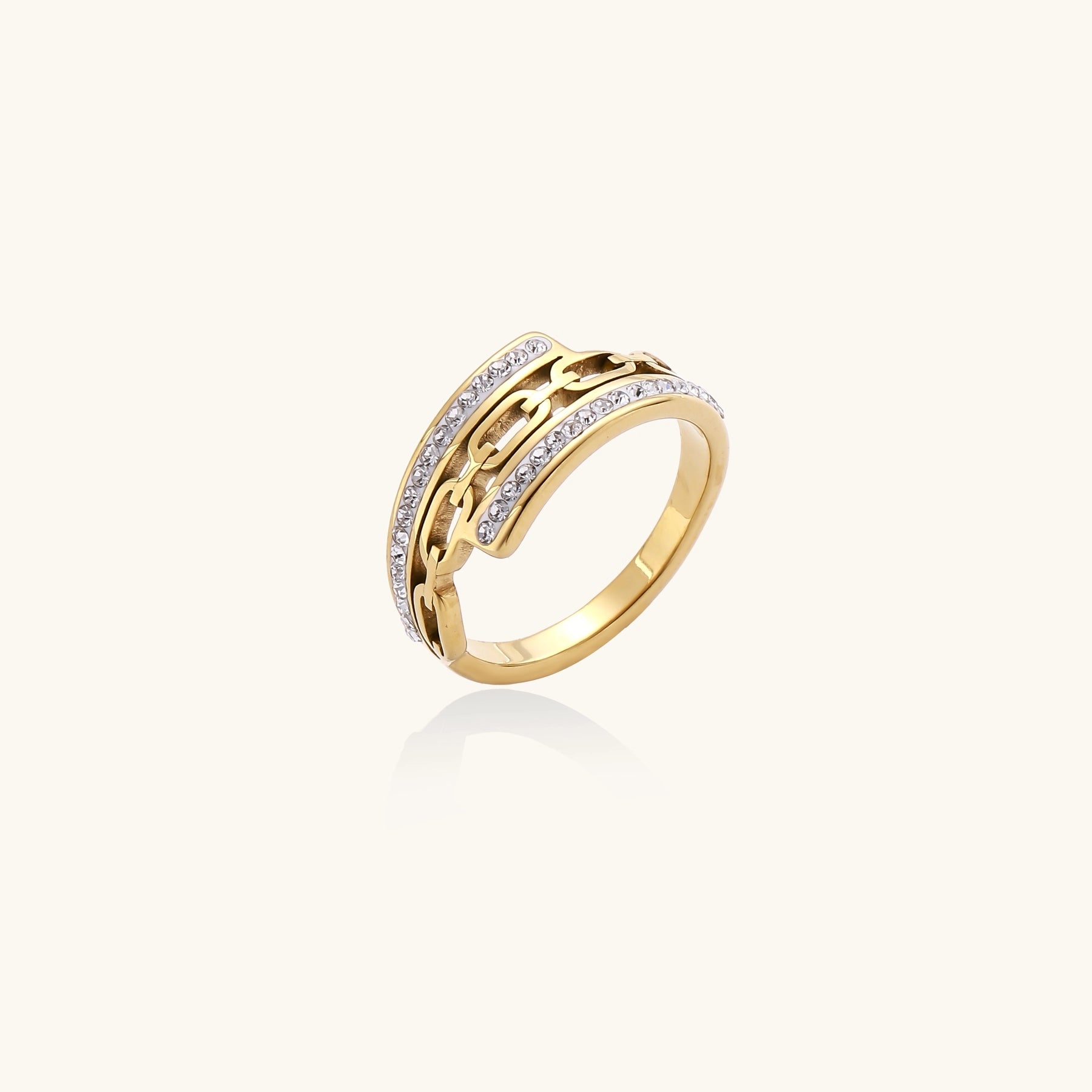 Gold-plated chain-link ring with rhinestone rows on cream background, showing bold geometric design and sparkling details.