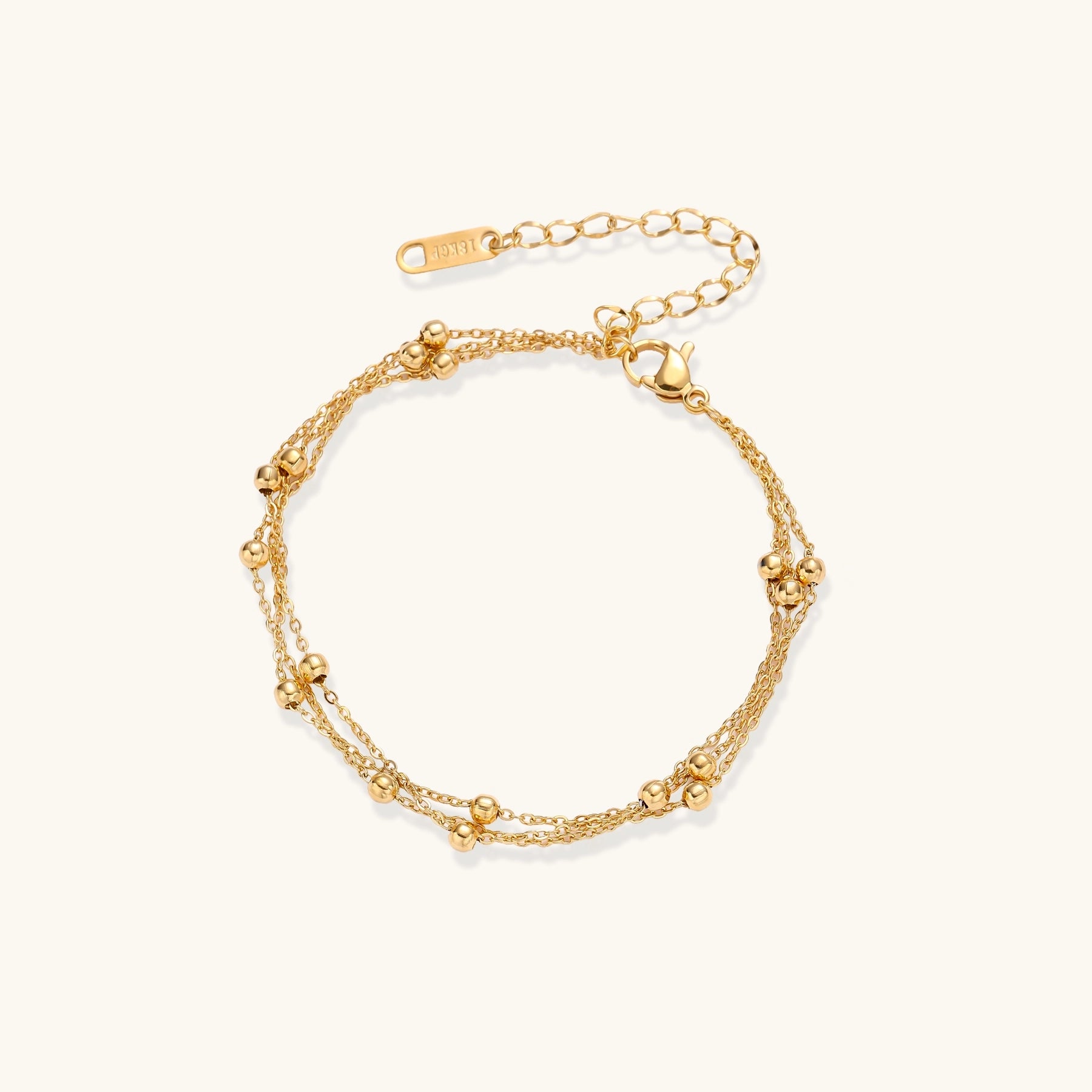 Delicate 18K gold plated bracelet with spherical beads on layered chains and adjustable extender on white background