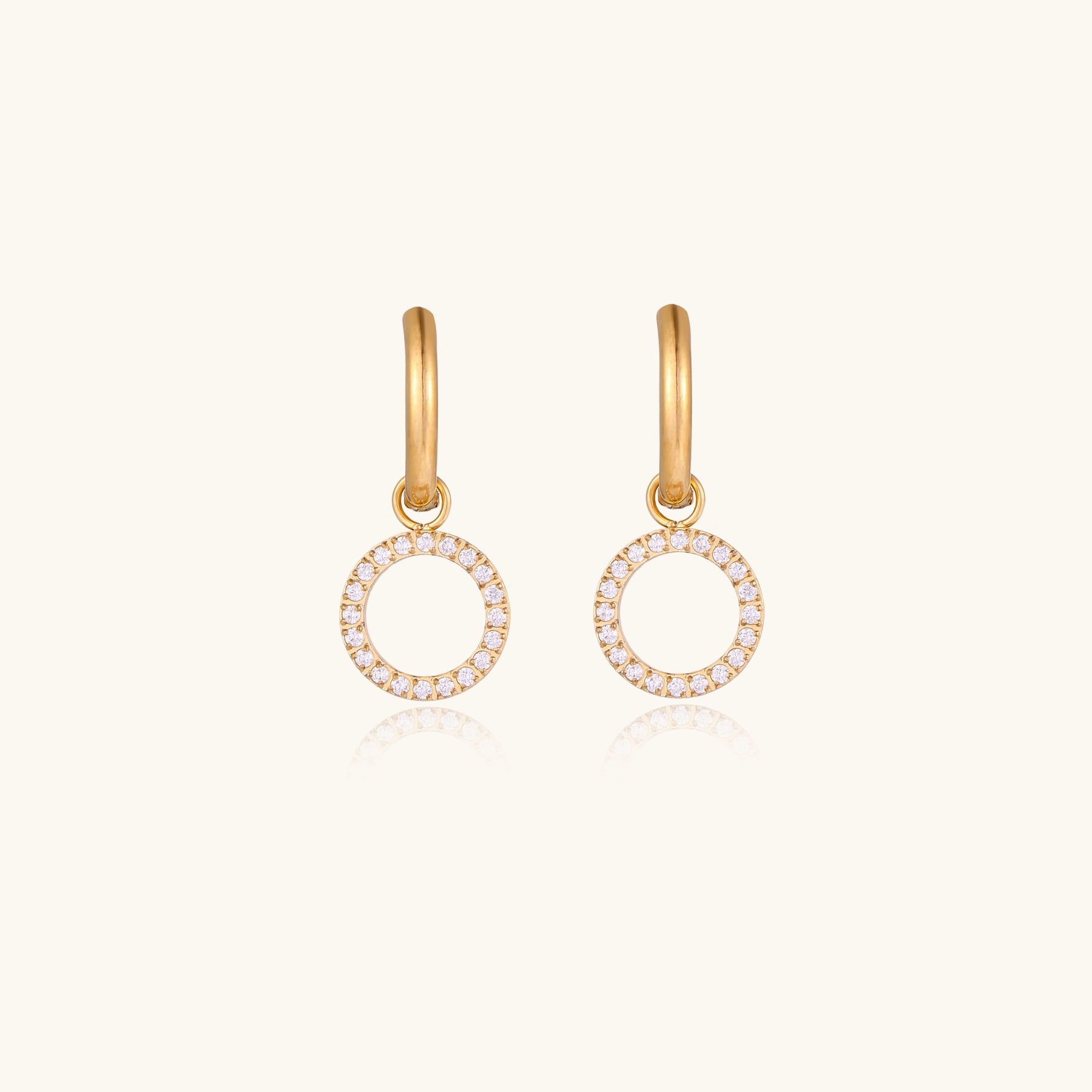 Gold-plated hoop earrings with circular cubic zirconia charm dangles displayed on neutral background.